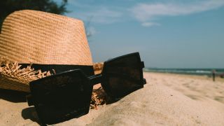 Sunglasses Beside Sun Hat on Sand