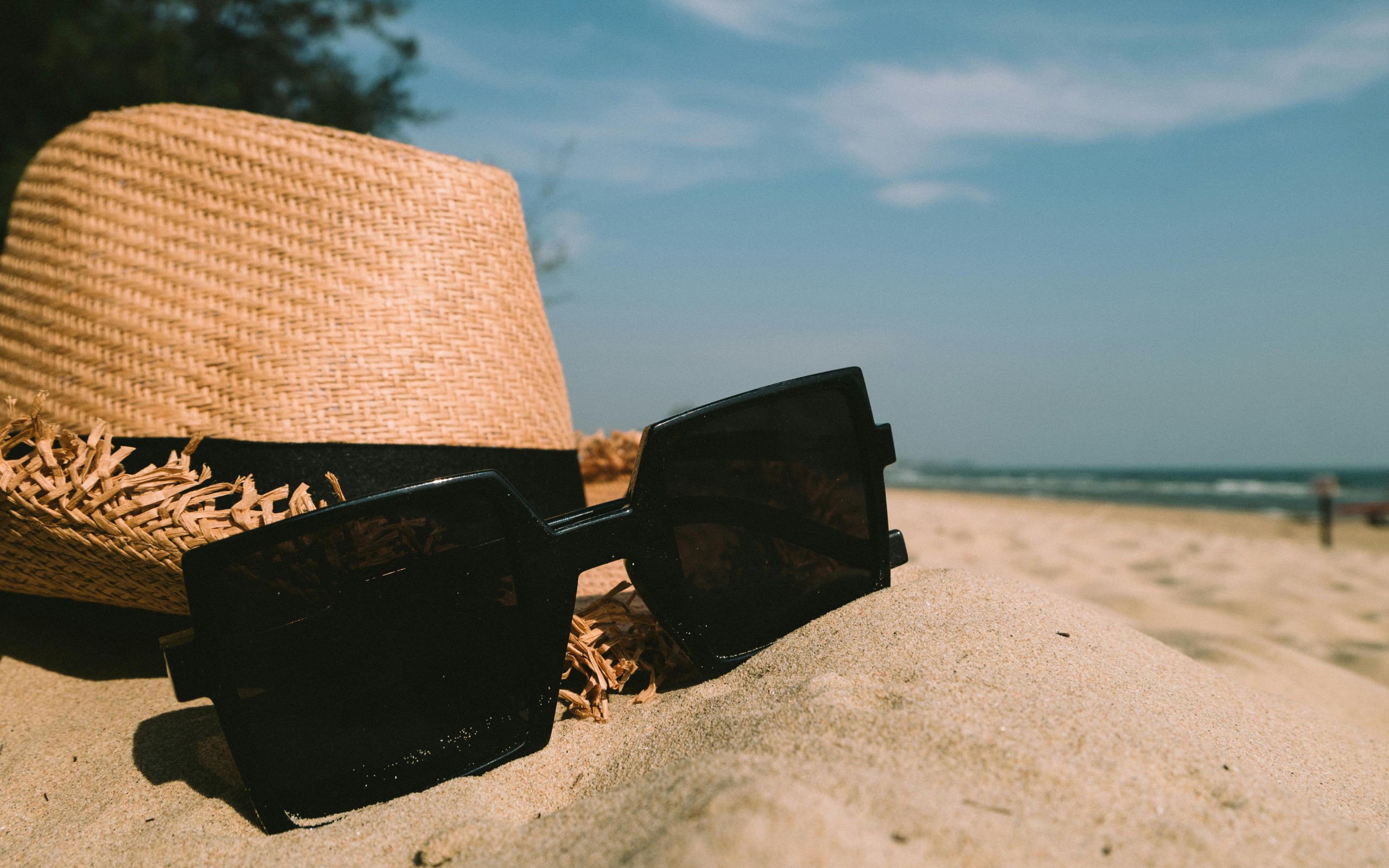 Sunglasses Beside Sun Hat on Sand