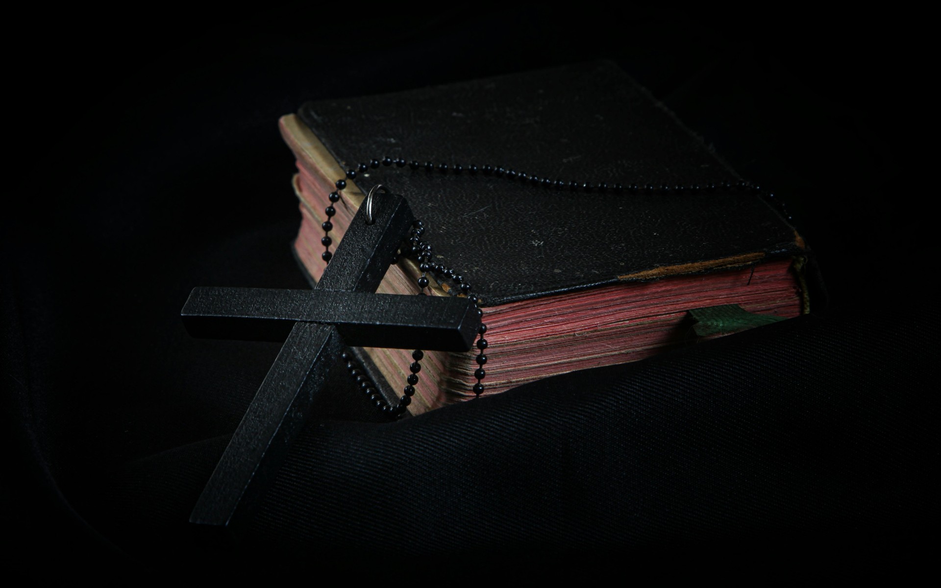 Black Cross leaning on Black Hardcover Bible