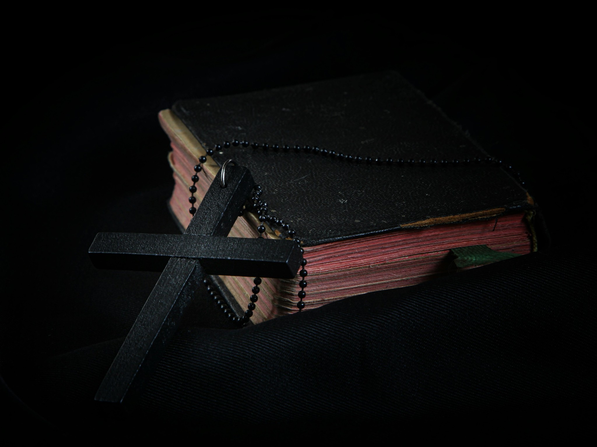 Black Cross leaning on Black Hardcover Bible