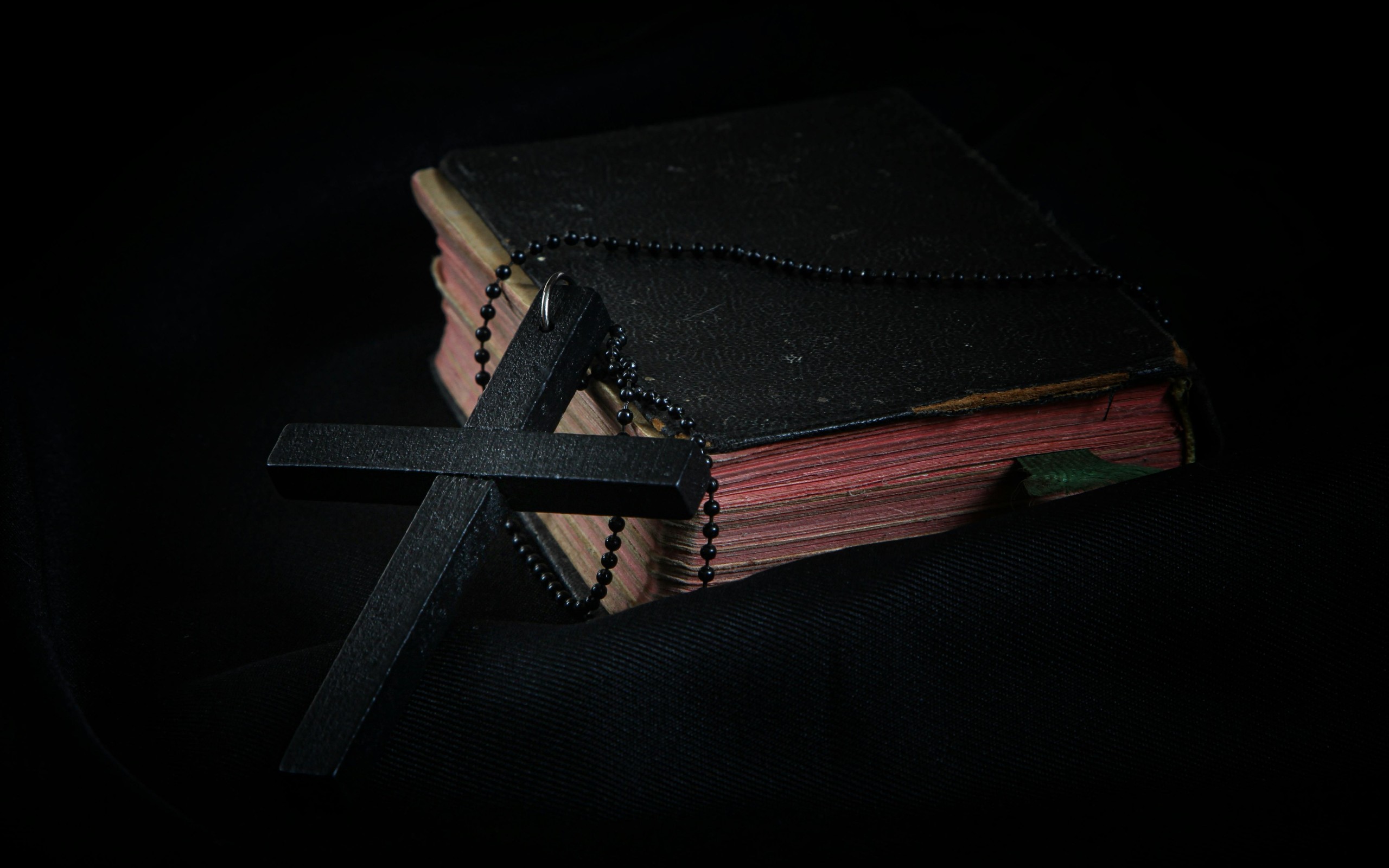 Black Cross leaning on Black Hardcover Bible