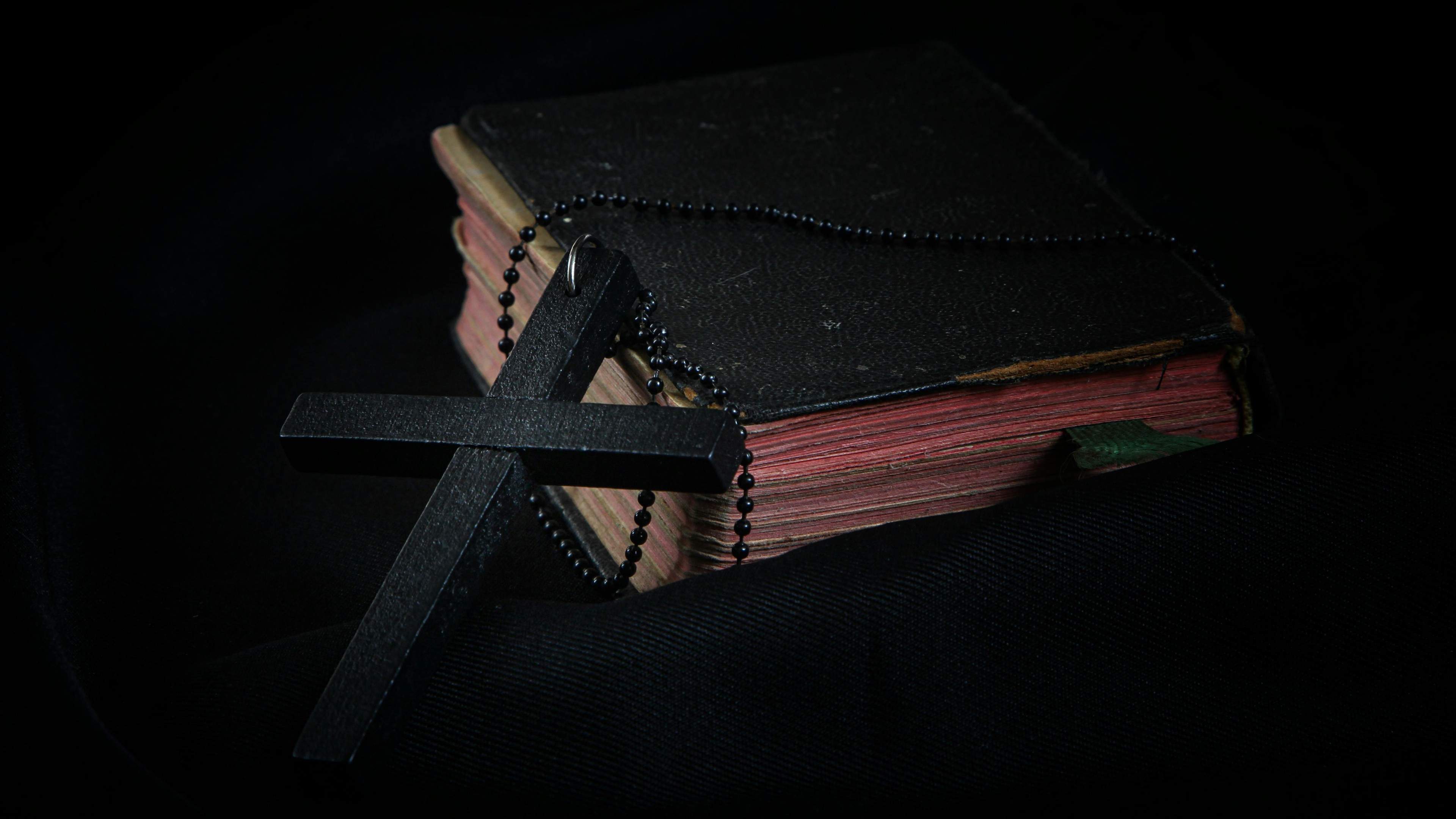 Black Cross leaning on Black Hardcover Bible