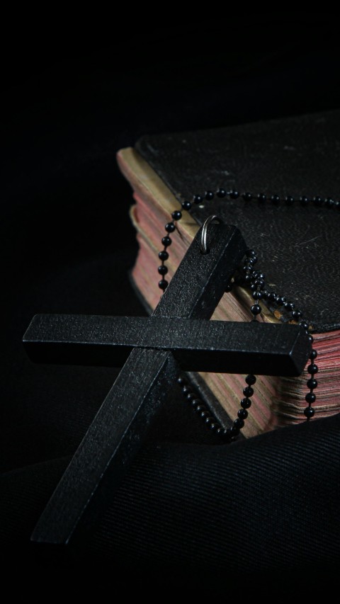 Black Cross leaning on Black Hardcover Bible