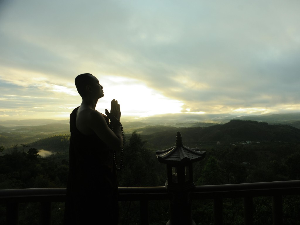 Monk Holding Prayer Beads Across Mountain