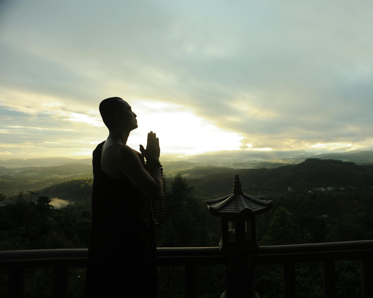 Monk Holding Prayer Beads Across Mountain