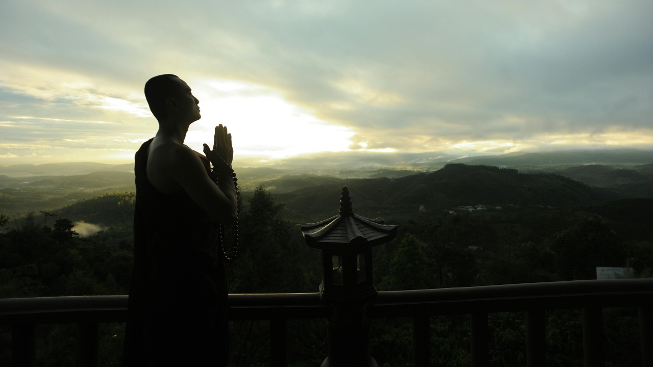 Monk Holding Prayer Beads Across Mountain