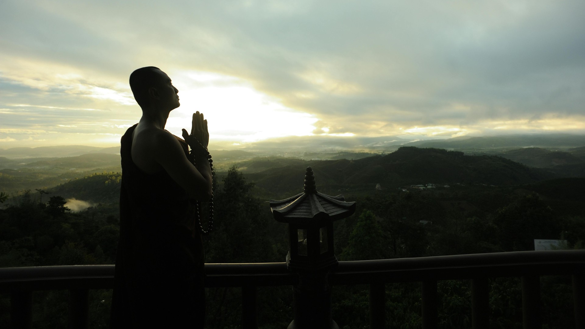Monk Holding Prayer Beads Across Mountain