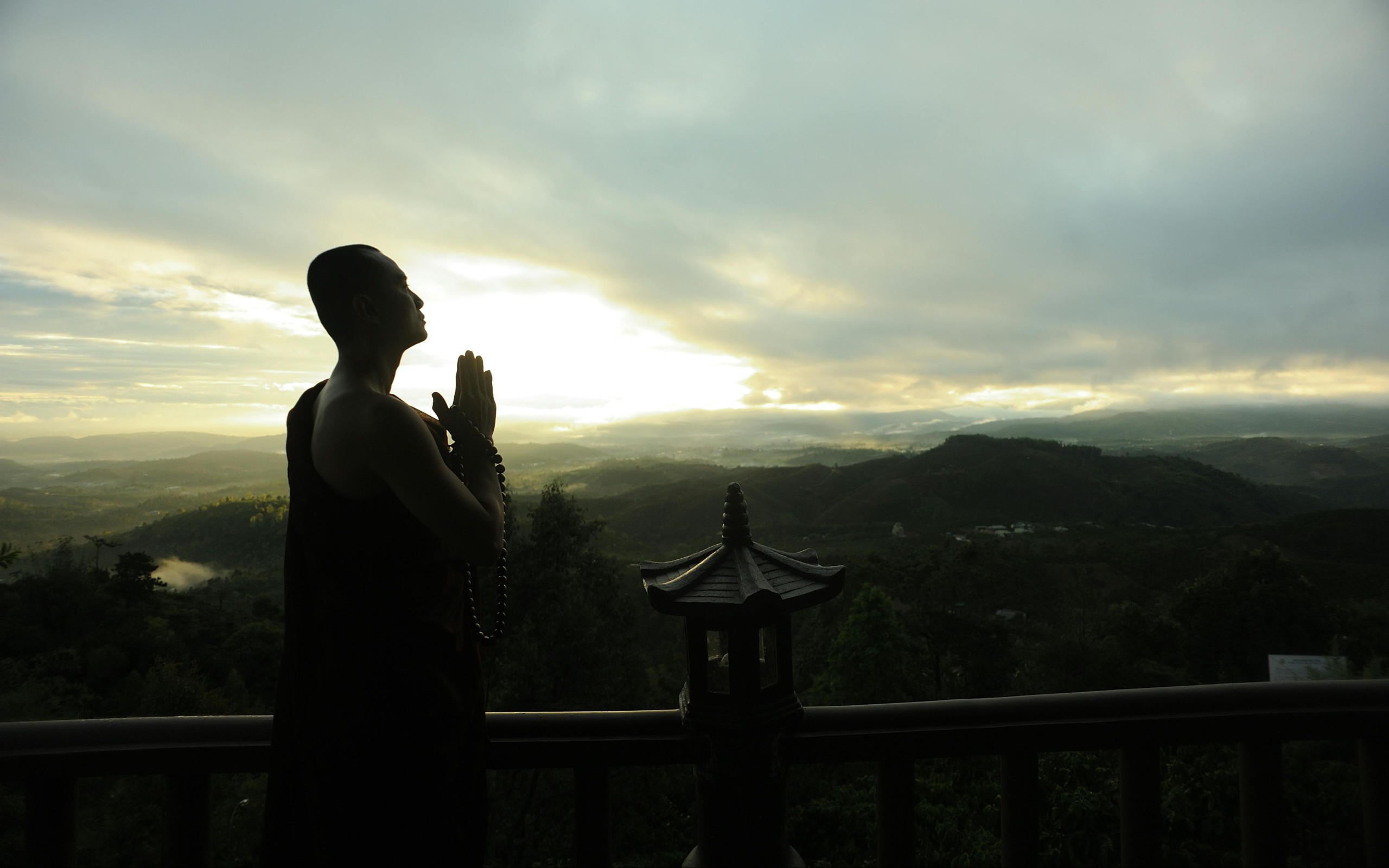 Monk Holding Prayer Beads Across Mountain