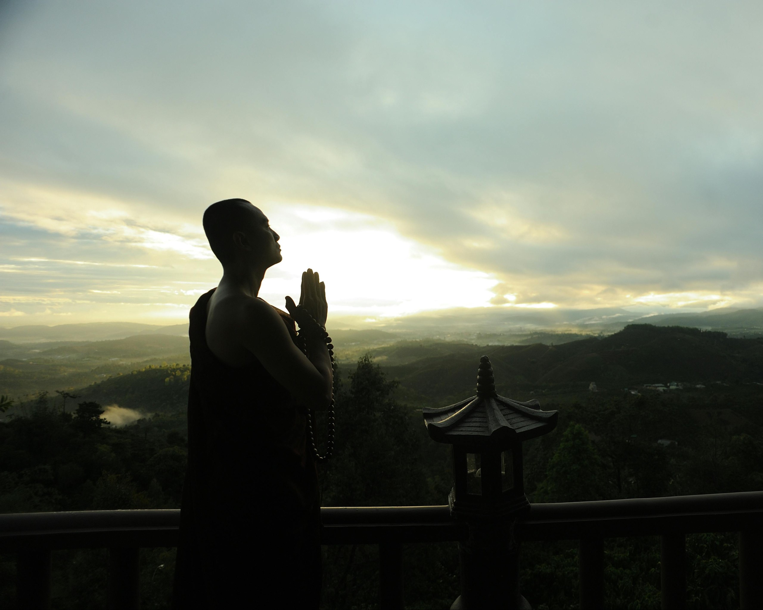 Monk Holding Prayer Beads Across Mountain