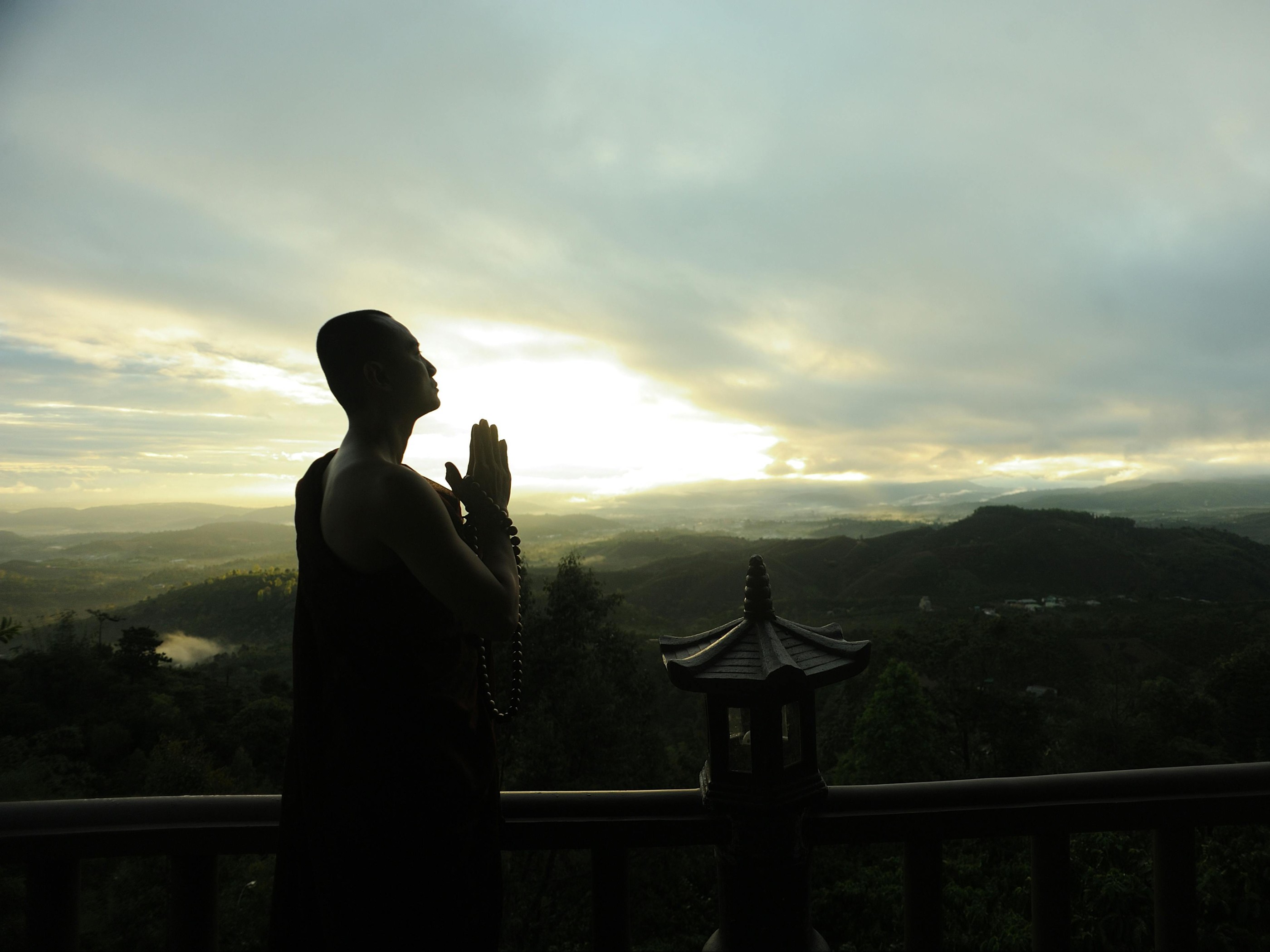 Monk Holding Prayer Beads Across Mountain