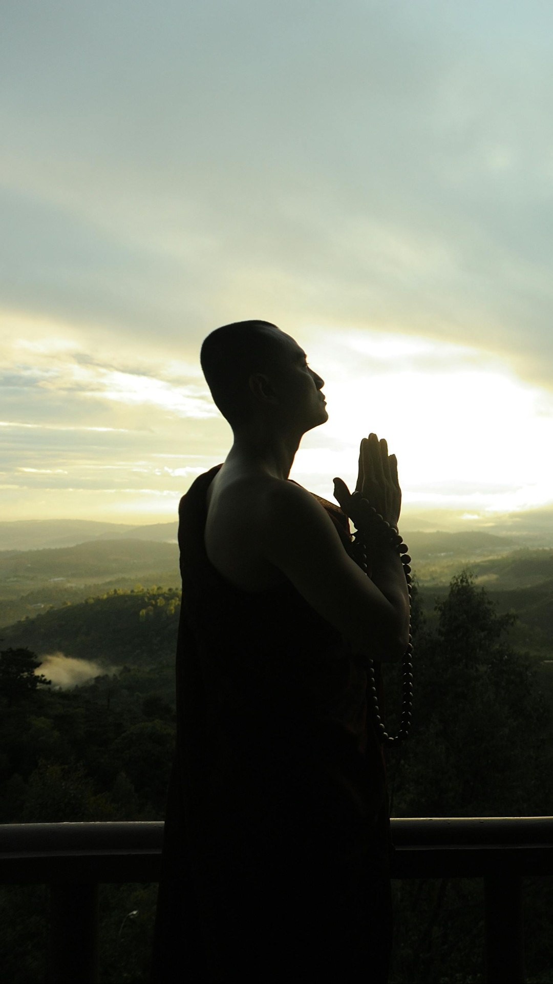 Monk Holding Prayer Beads Across Mountain