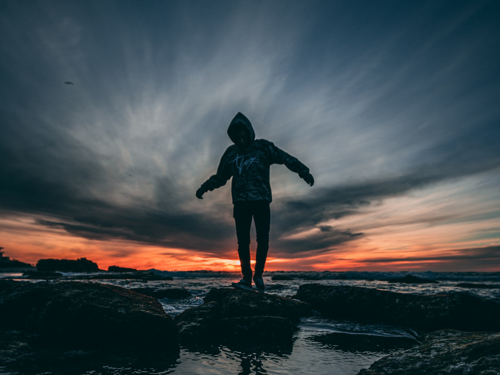 Person Wearing Hoodie Standing on Rock