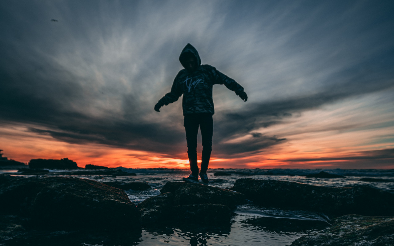 Person Wearing Hoodie Standing on Rock