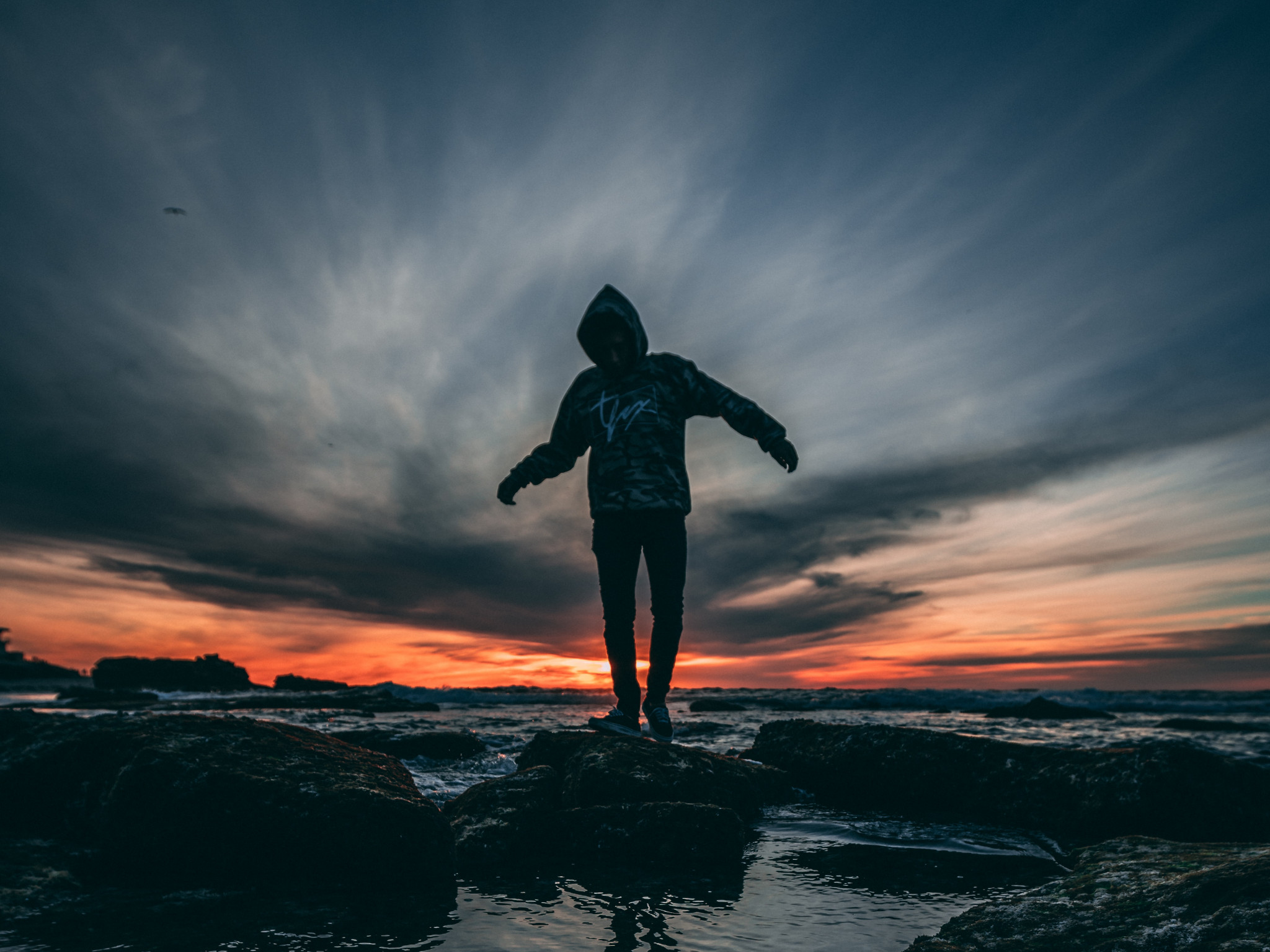 Person Wearing Hoodie Standing on Rock