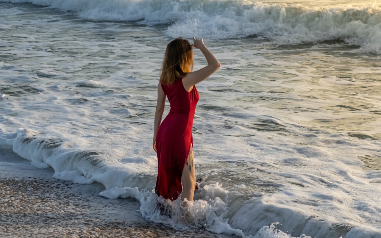 Woman in Red Dress Standing on Beach