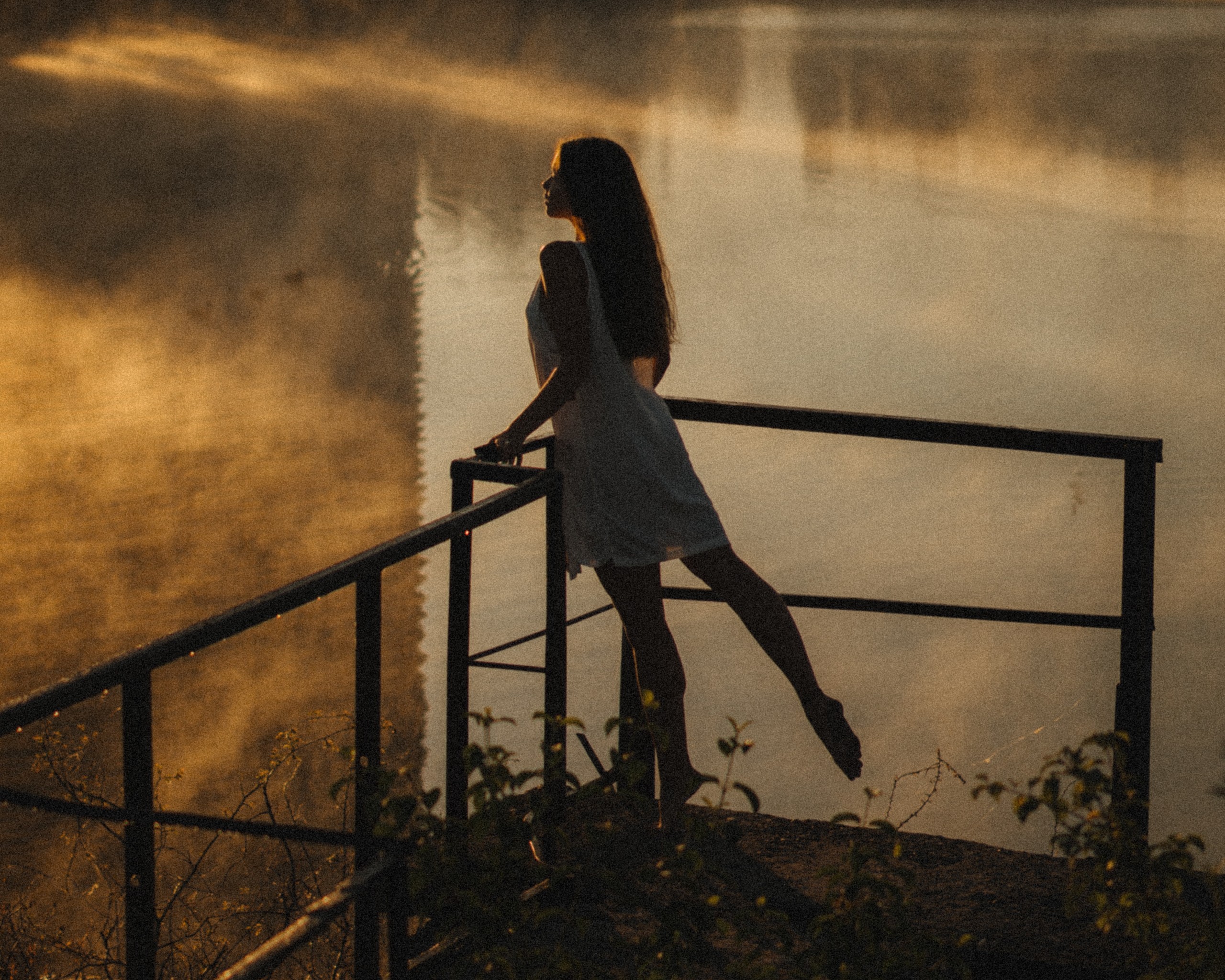 Woman Leaning against Railing By a Pond