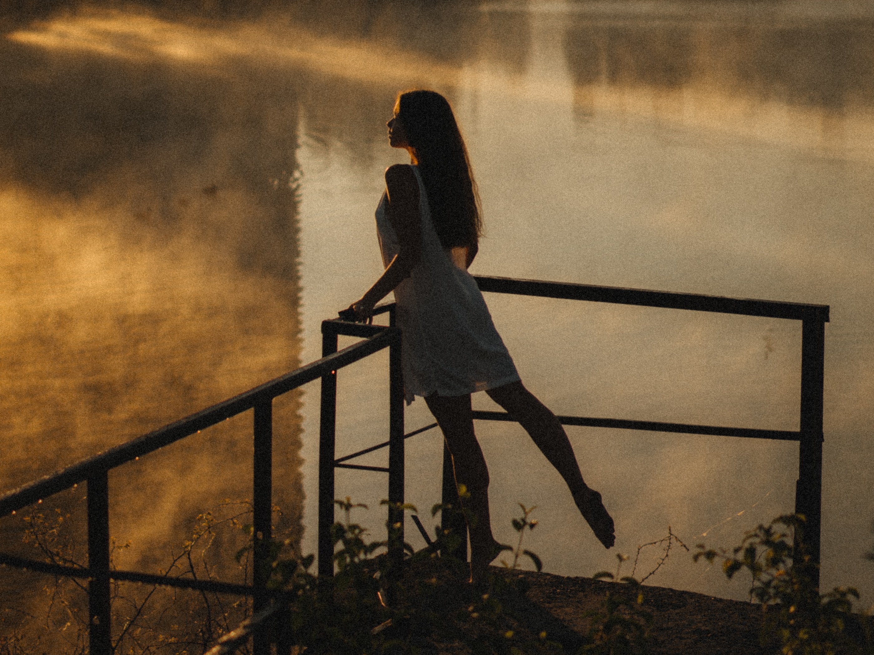 Woman Leaning against Railing By a Pond