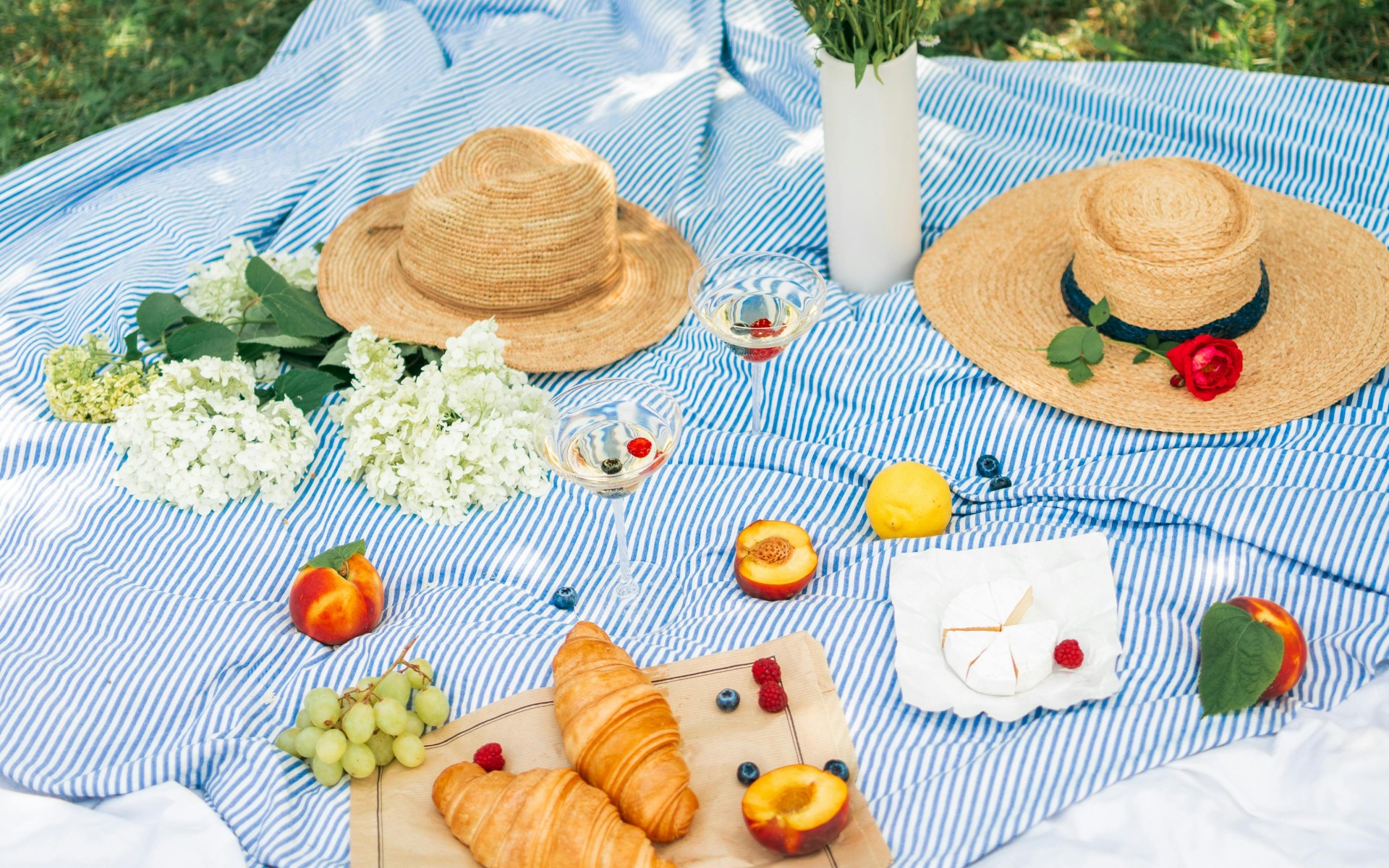 Food Beside the Flowers and Straw Hats on a Picnic Blanket